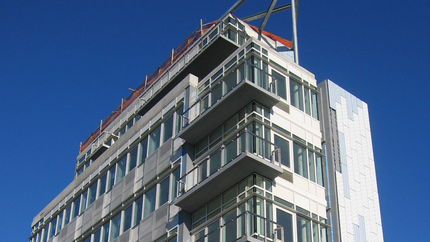 The completed cast-in-place concrete building totals 34,500 SF with large cantilever balconies and structural steel canopy. Photo courtesy Studio V Architecture.