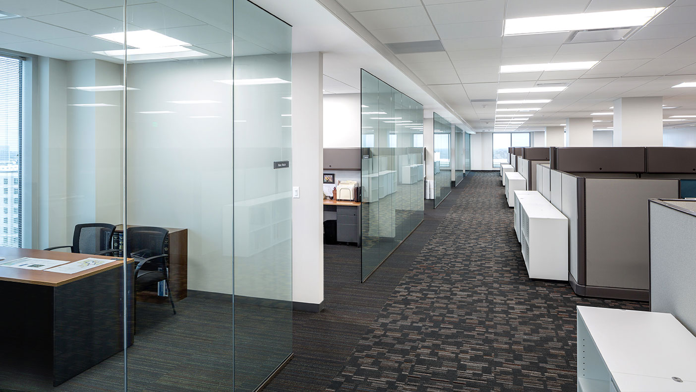 Glass-enclosed offices line the perimeter with floor-to-ceiling exterior and interior windows that facilitate daylighting, and low-partitioned cubicles allowing natural light to flow throughout the office.