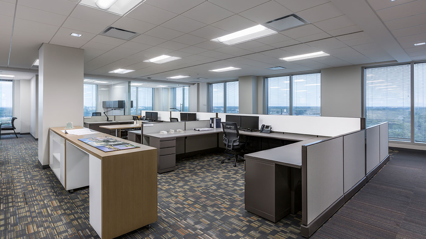 Shared work tables between cubicles support interoffice collaboration.