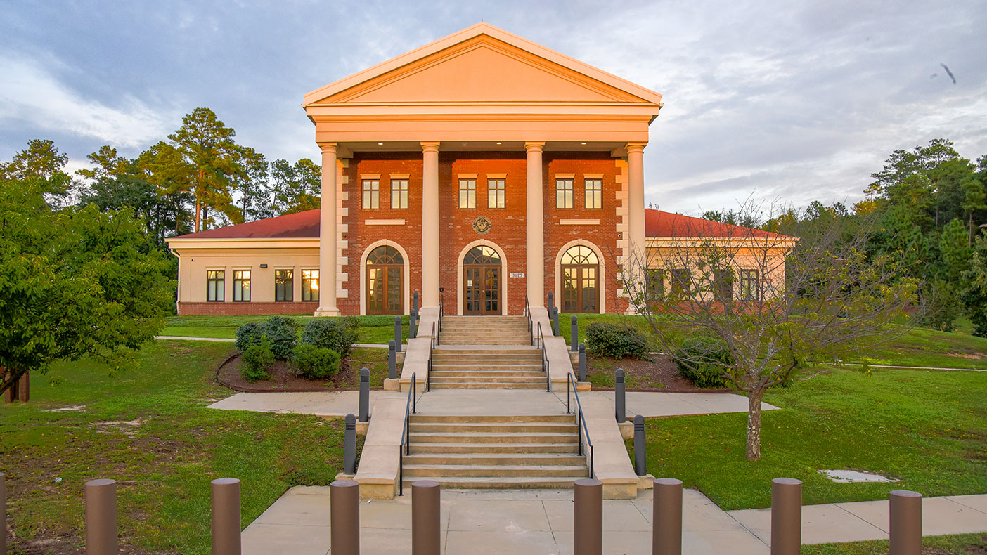 A tall pediment-capped portico serves as the main entry and provides a strong civic statement appropriate to the judicial processes at the base.