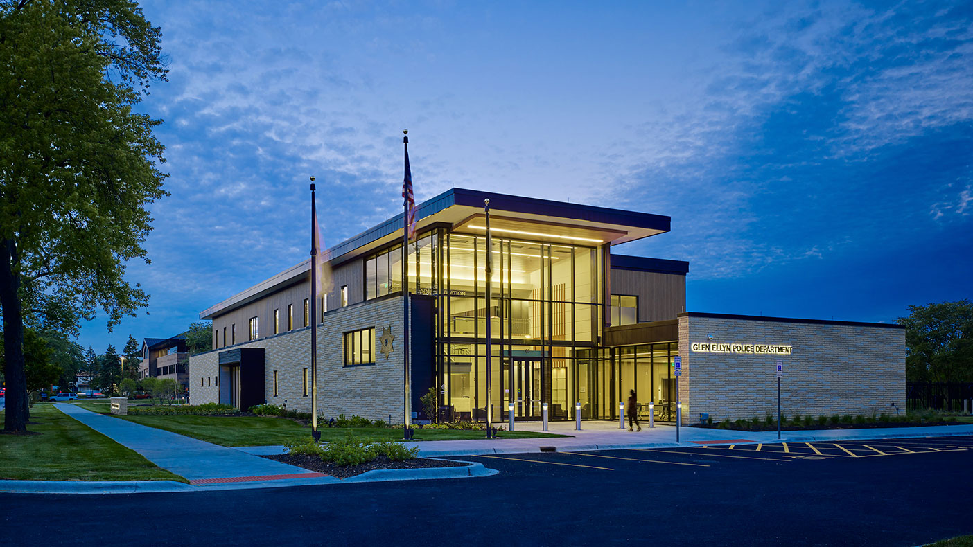 A southwest corner view of the two-story public entry volume at dusk.