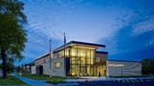 A southwest corner view of the two-story public entry volume at dusk.