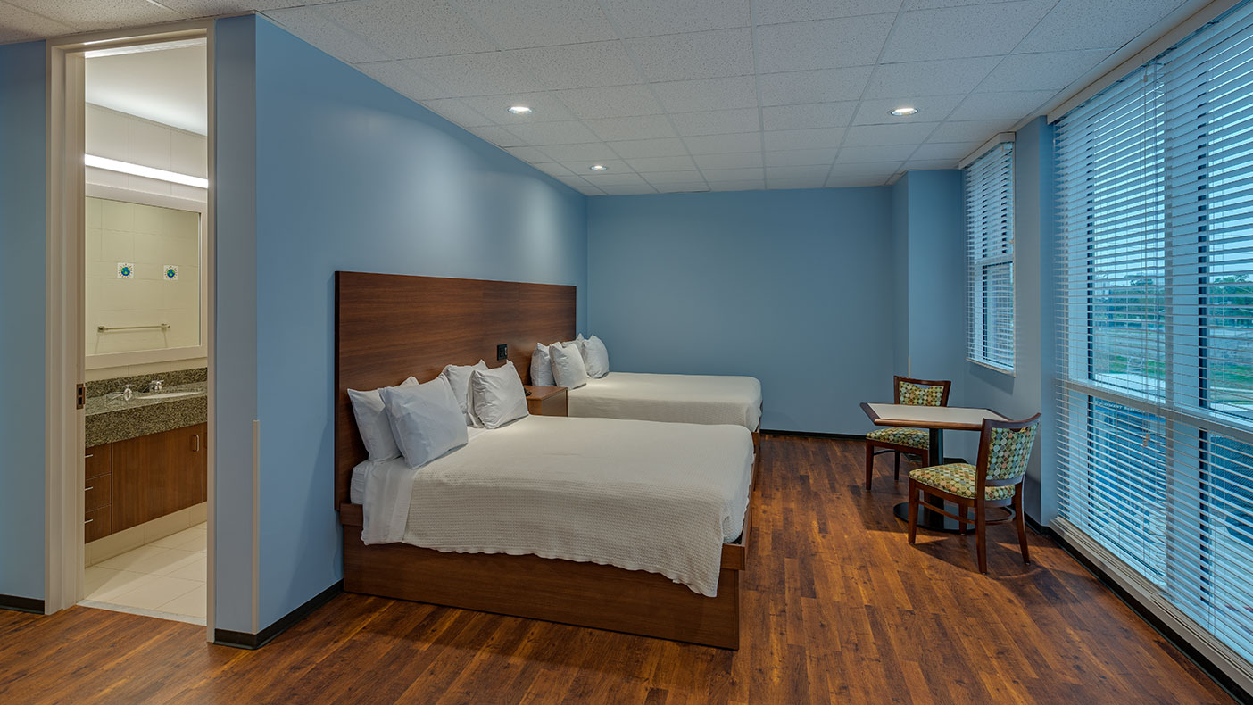 Spacious guest rooms featuring large windows allowing for lots of natural light, two queen beds, and a wheelchair-accessible bathroom. 