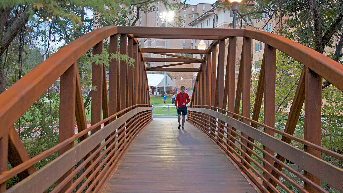 The new 110-foot bowstring truss pedestrian bridge crosses Waller Creek, improving the connection to the general campus and providing a direct link to the Recreational Sports Center to the west.