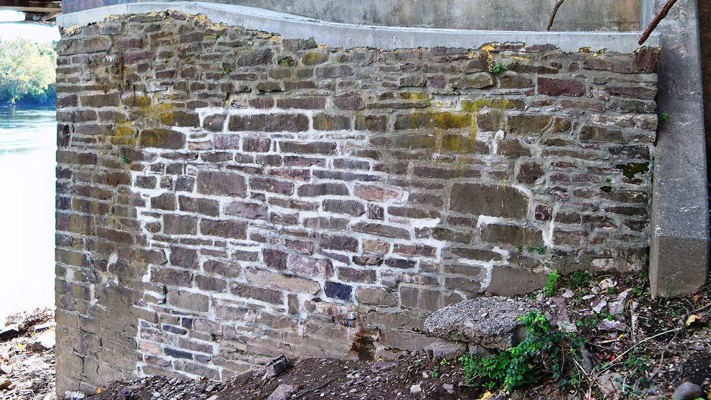 To address bulging and cracking of the masonry wingwalls, internal structural repair measures were developed in lieu of an aesthetically disruptive exterior buttress system.