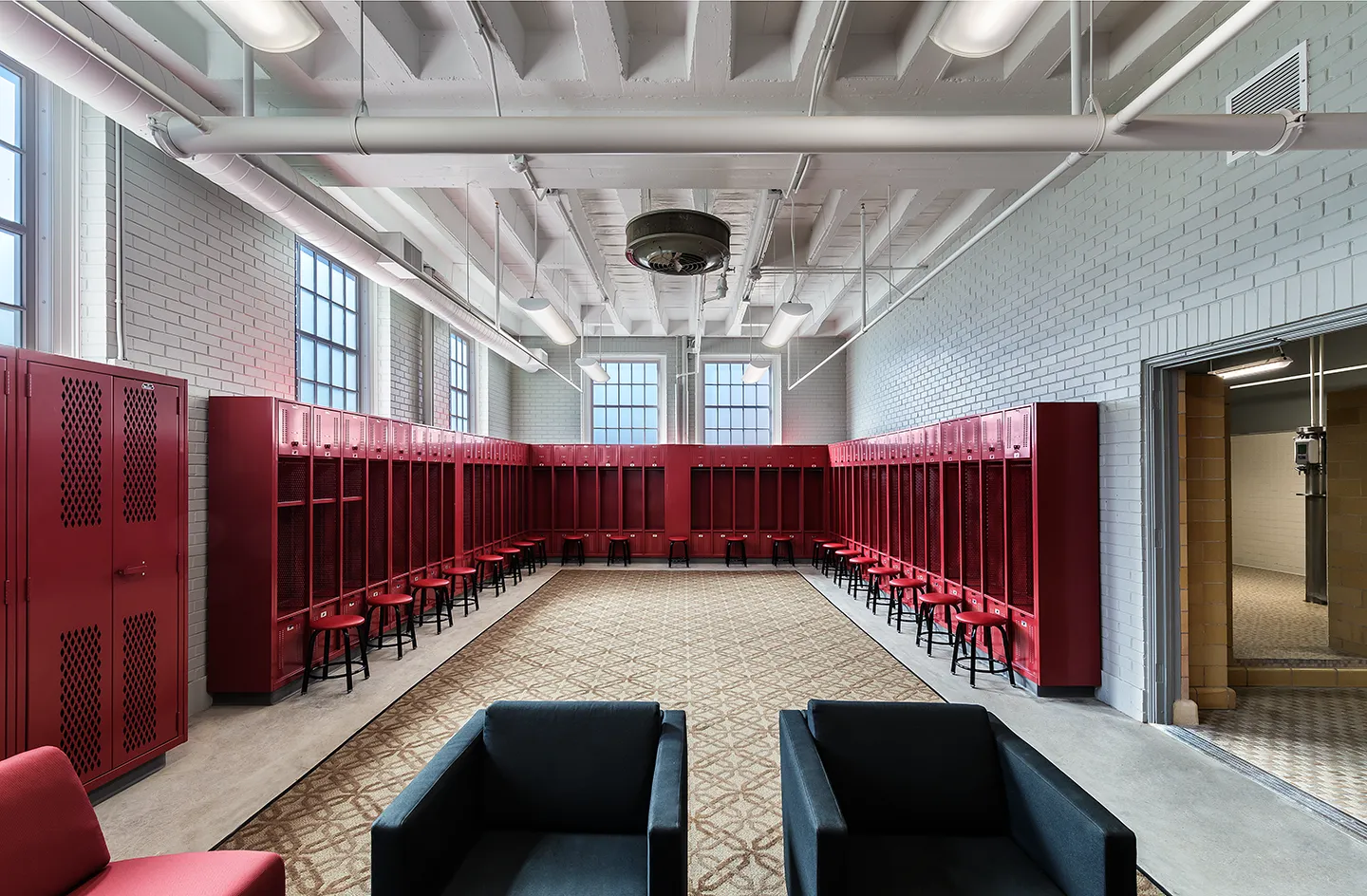 Throughout the lower level of Eby Fieldhouse, locker rooms were added and renovated. This baseball locker room benefits from the character of the 1930s building with high exposed ceilings, natural light, exposed brick, and original ceramic tiles.