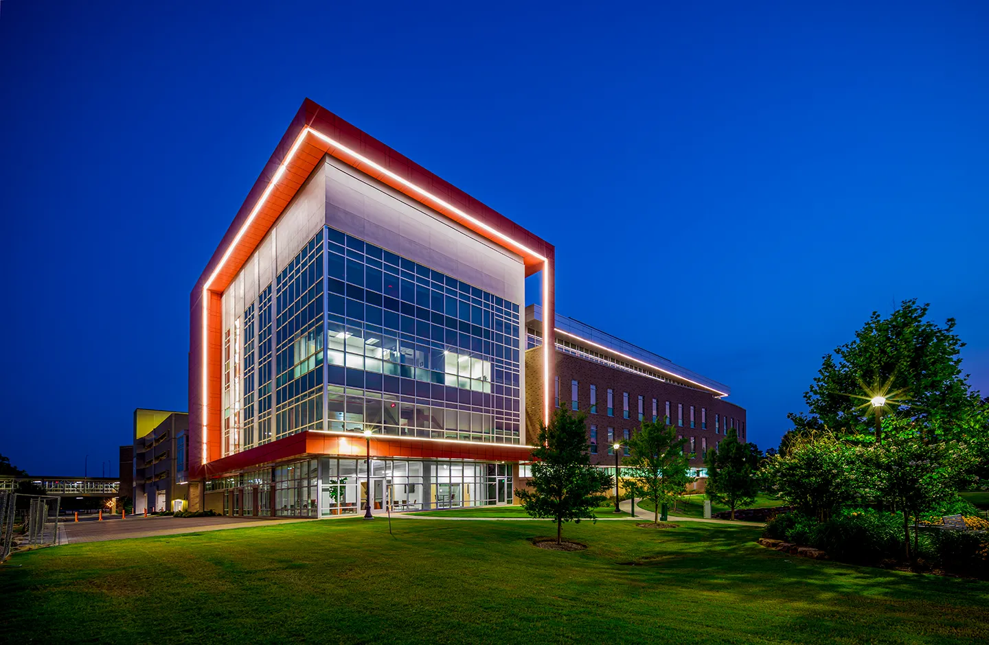 Exterior LED lighting reinforces OSU’s bright orange brand and highlights the building’s unique angled features, adding nighttime visual interest to the elevated site.