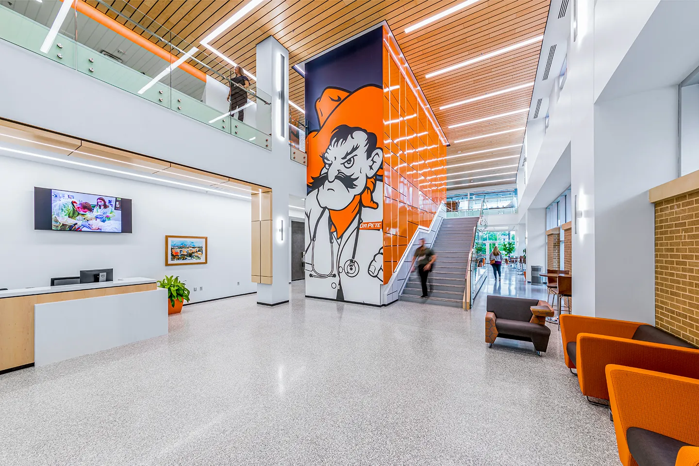 The lobby’s elevator reinforces branding and campus pride, becoming a welcoming entrance focal point accented with bold color patterns and LED lighting.