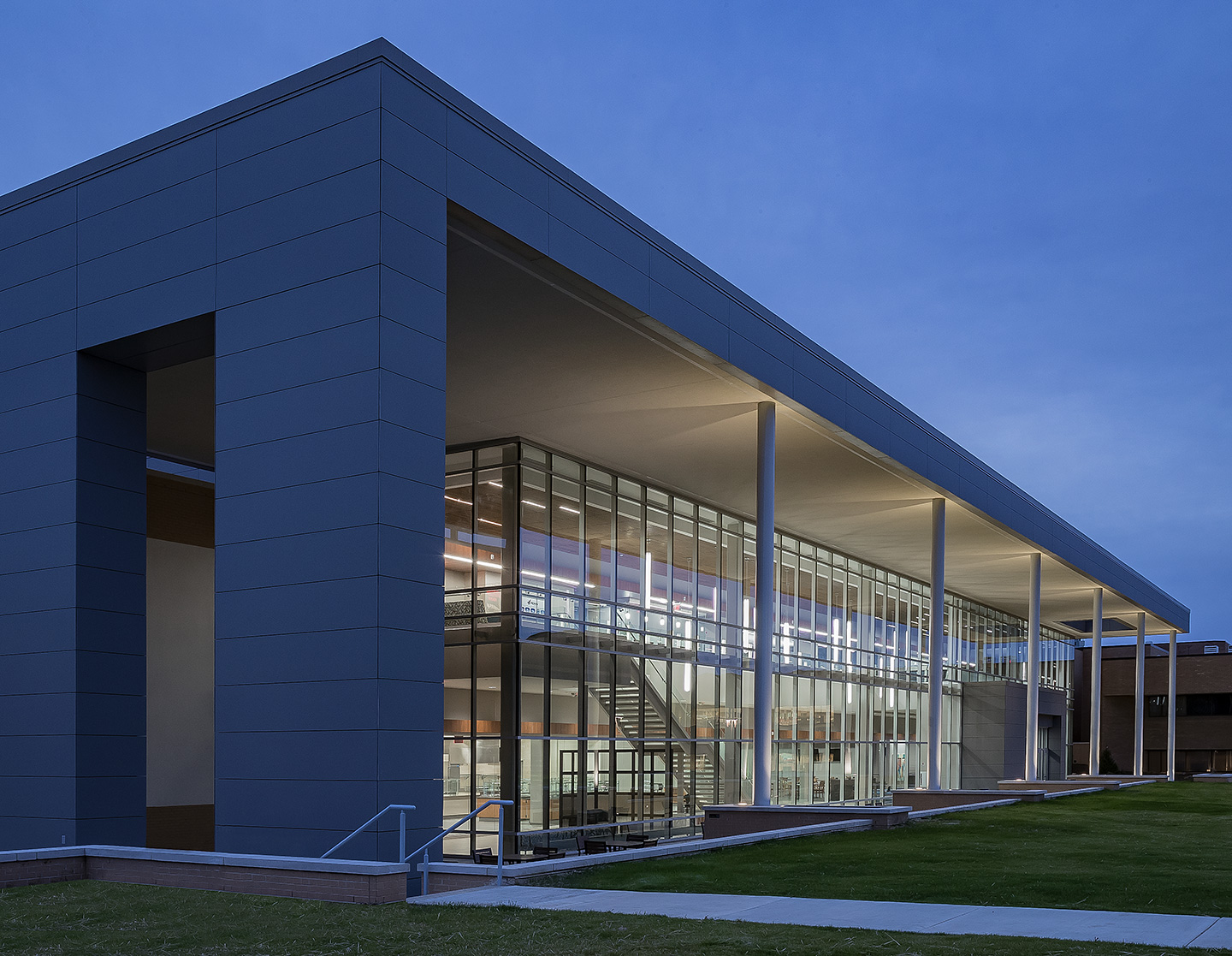 The two-story glass expanse reflects out on to the gathering lawn and provides views to the wooded campus.