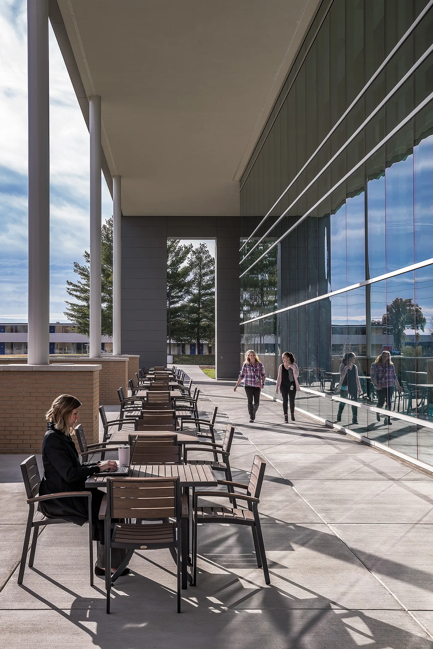 The building’s two-story glass façade and exterior workspace connect staff to nature and sheltered seating areas.  An outdoor screen under the canopy provides a presentation opportunity for all company gatherings.